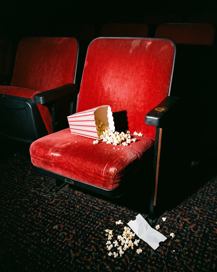 Spilled popcorn on a red cinema seat after the last show