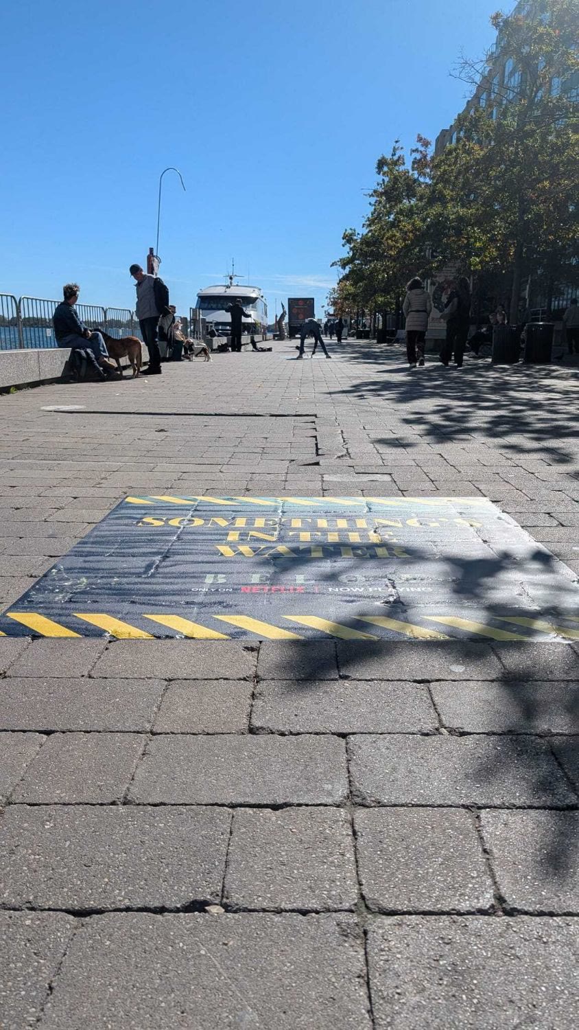 A floor graphic on the waterfront promenade reading Something's in the water, Below, only on Netflix, now playing