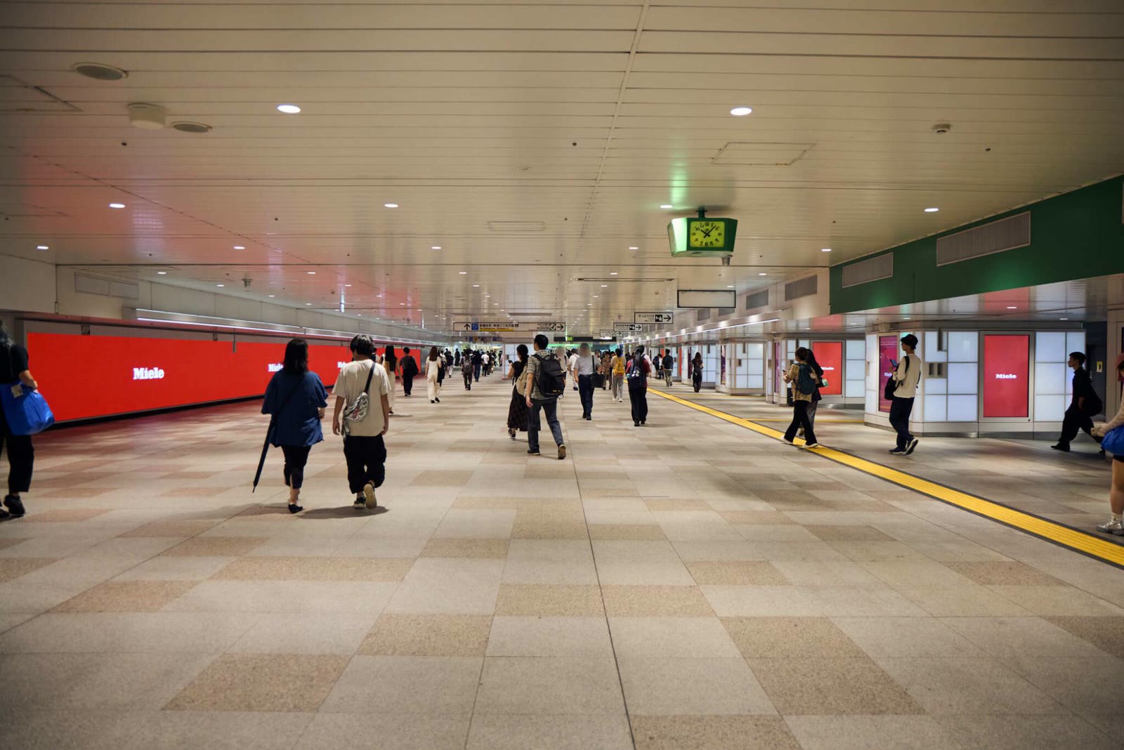 The East-West Free Passage of JR Shinjuku station, the Miele logo on the wall on the left and on the pillar screens on the right