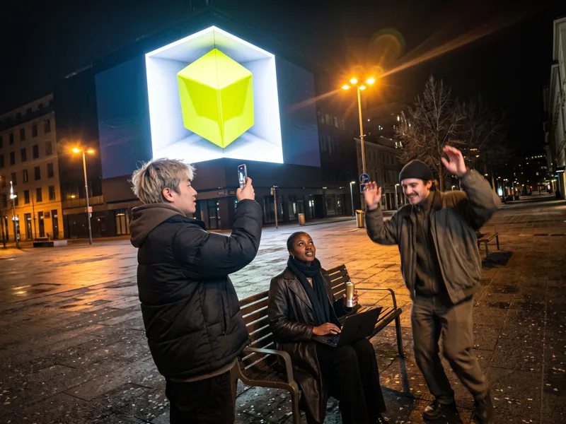 The team checks a test cube on a corner billboard at night