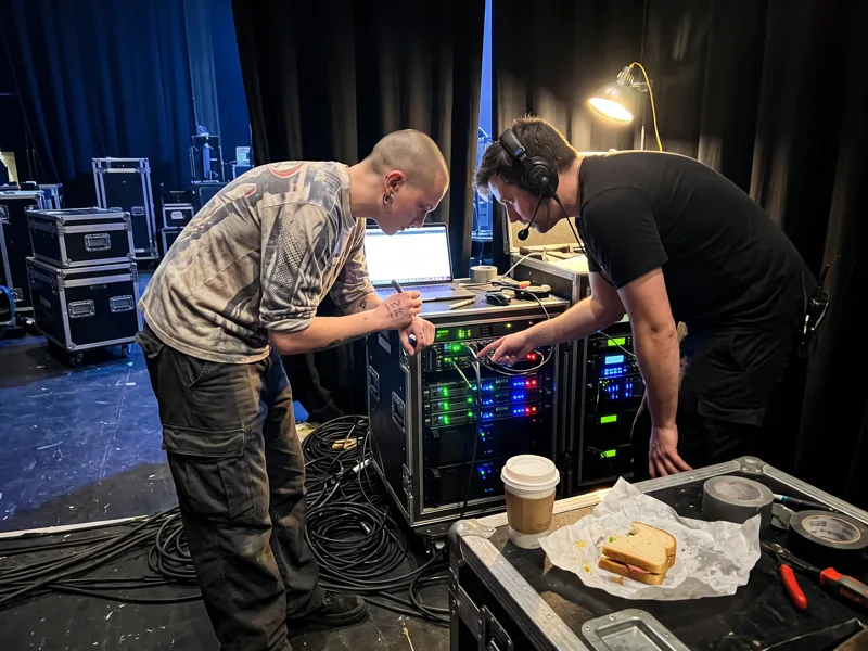 A creative checks the playback setup with the AV technician backstage